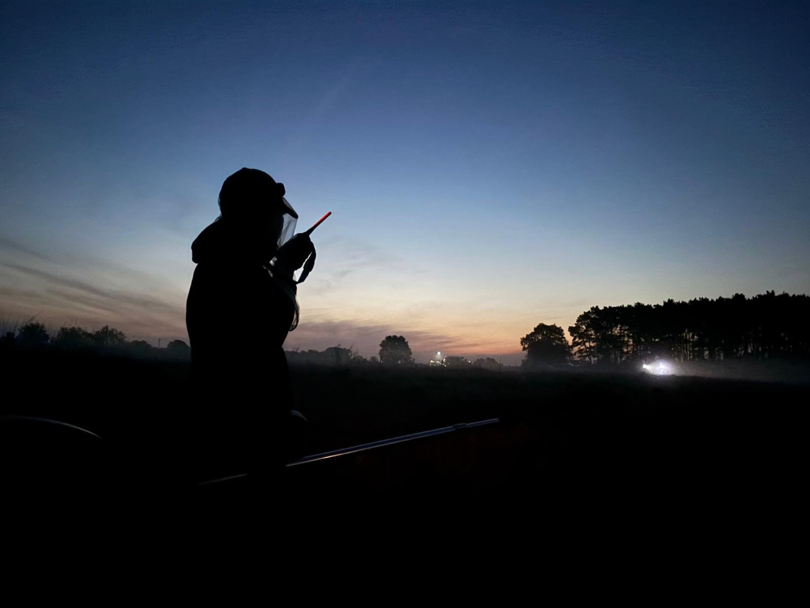 Silhouette einer Person mit Funkgerät in der Morgendämmerung