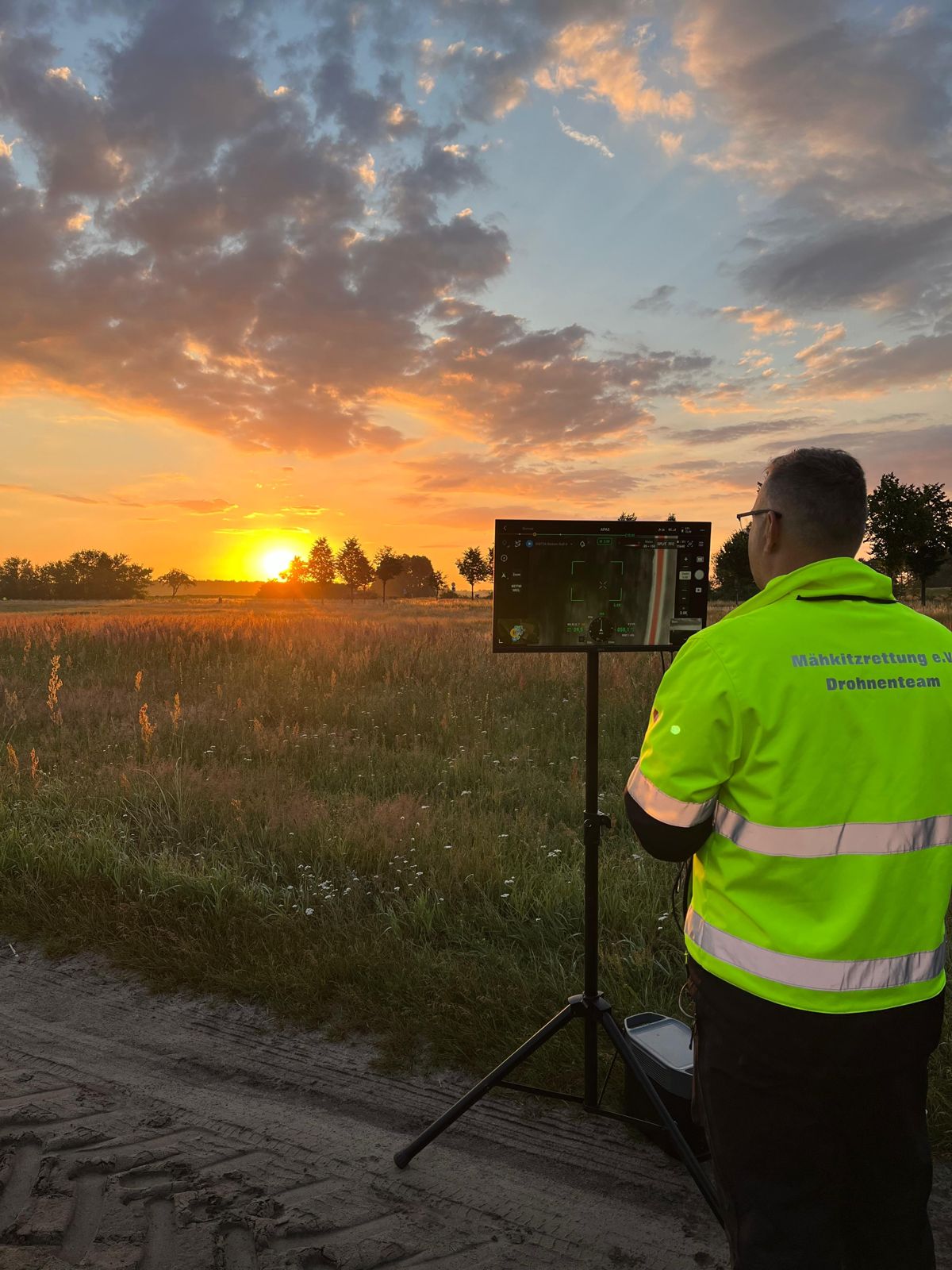 Drohnenpilot im Sonnenaufgang vor dem Monitor mit dem Livebild